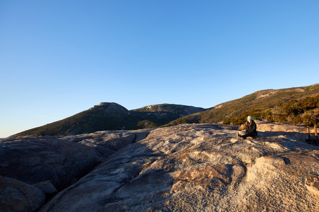 person on granite slab near bushland