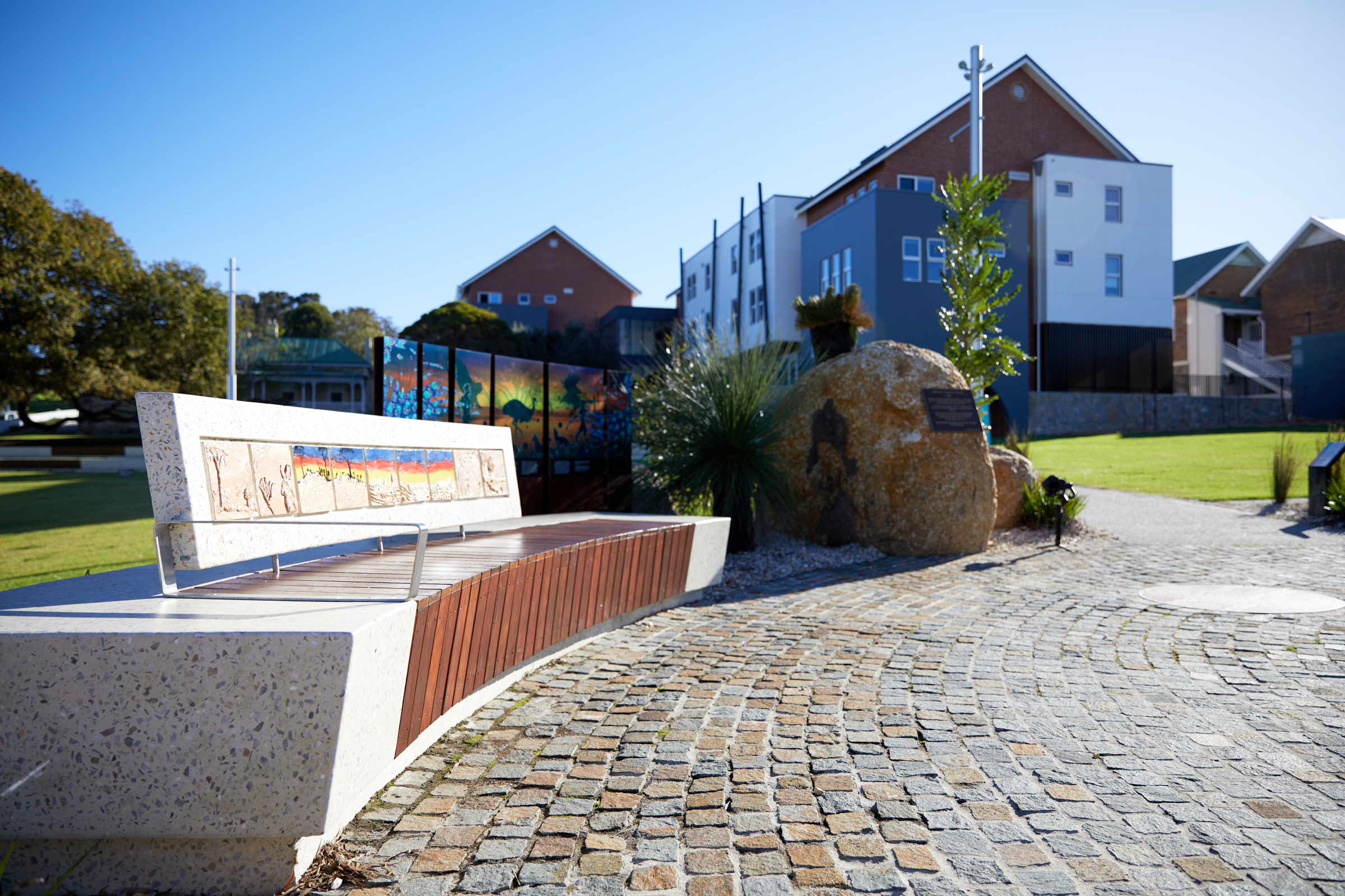 "A curved outdoor bench featuring tiled artwork in Alison Hartman Gardens.