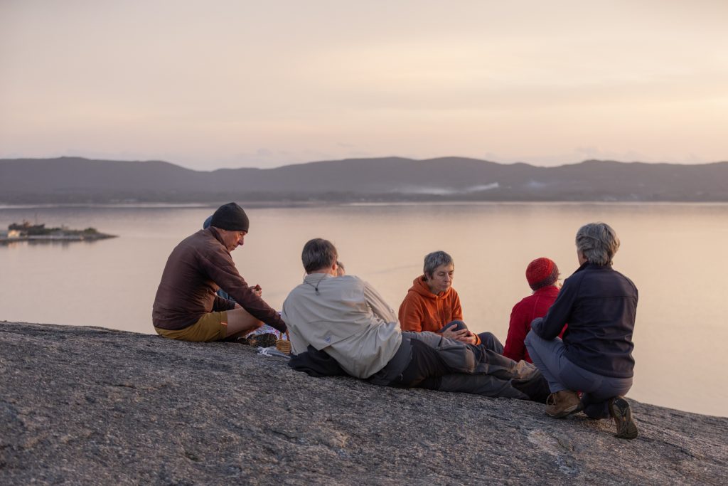 group of people picnic on granite slab overlooking water