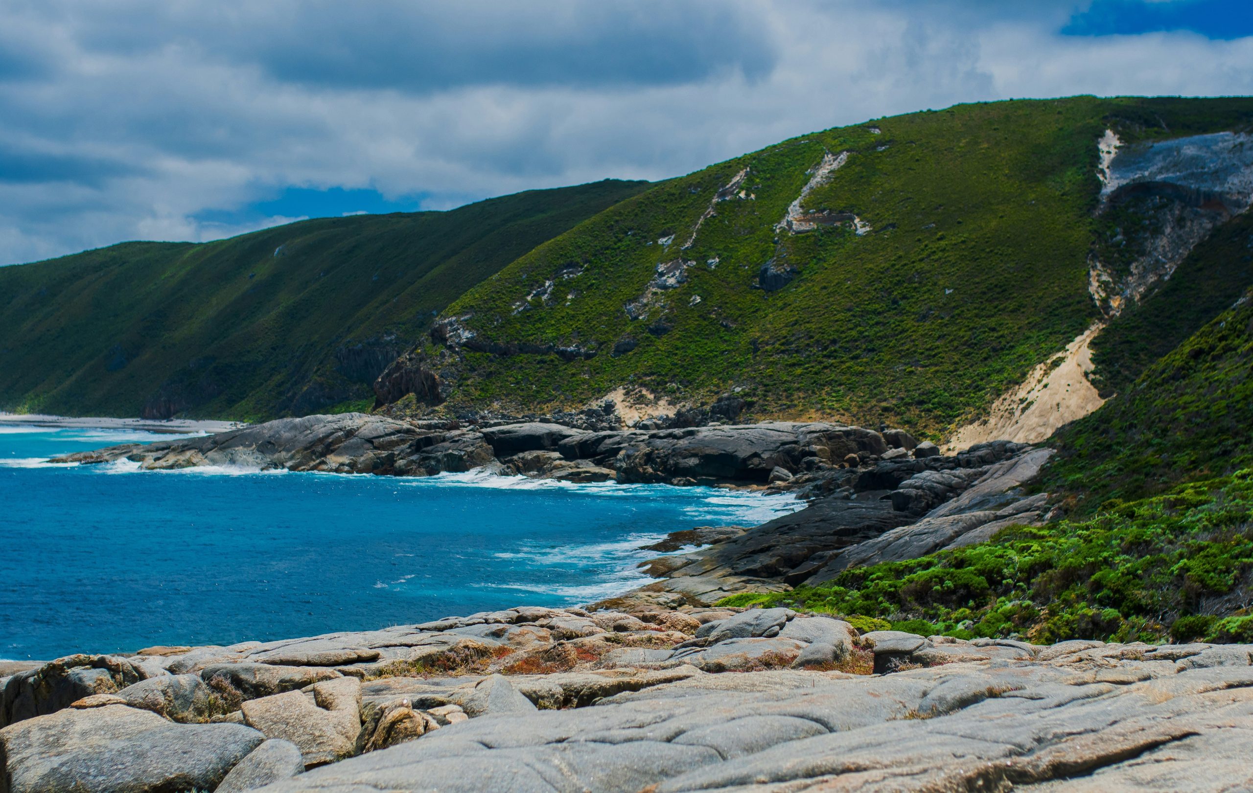 The rugged granite rocks and vibrant green coastal hills of the Southern Ocean coastline, a breathtaking natural attraction to explore in Albany WA.