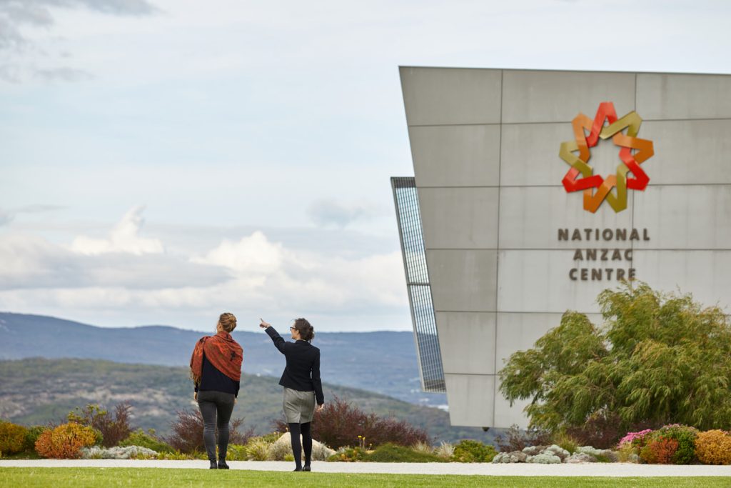 two women walking across lawn near building